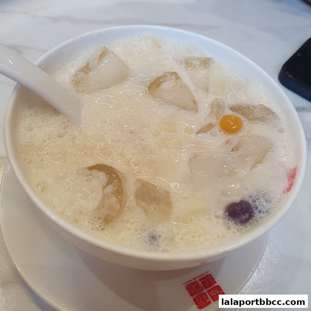 A refreshing bowl of dessert with ice, milk, and colorful toppings.