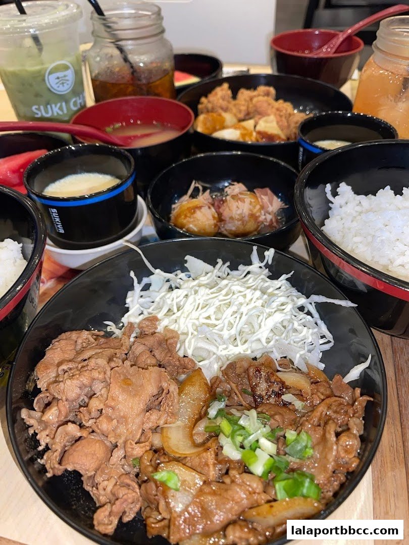 A close-up of a delicious Japanese meal with beef bowls, miso soup, and drinks.
