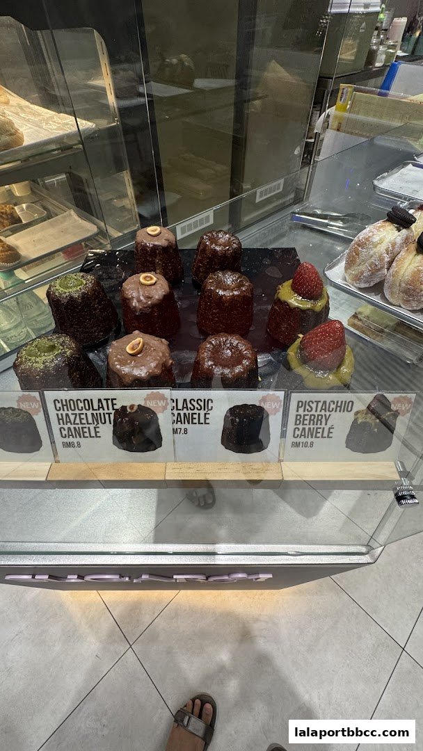 A display case filled with various types of canelé pastries, some with toppings.