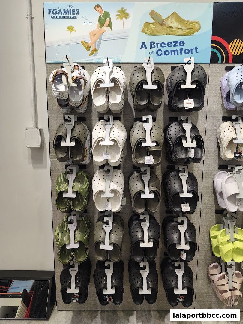 A display wall showcasing various Skechers Foamies clogs and sandals in different colors.