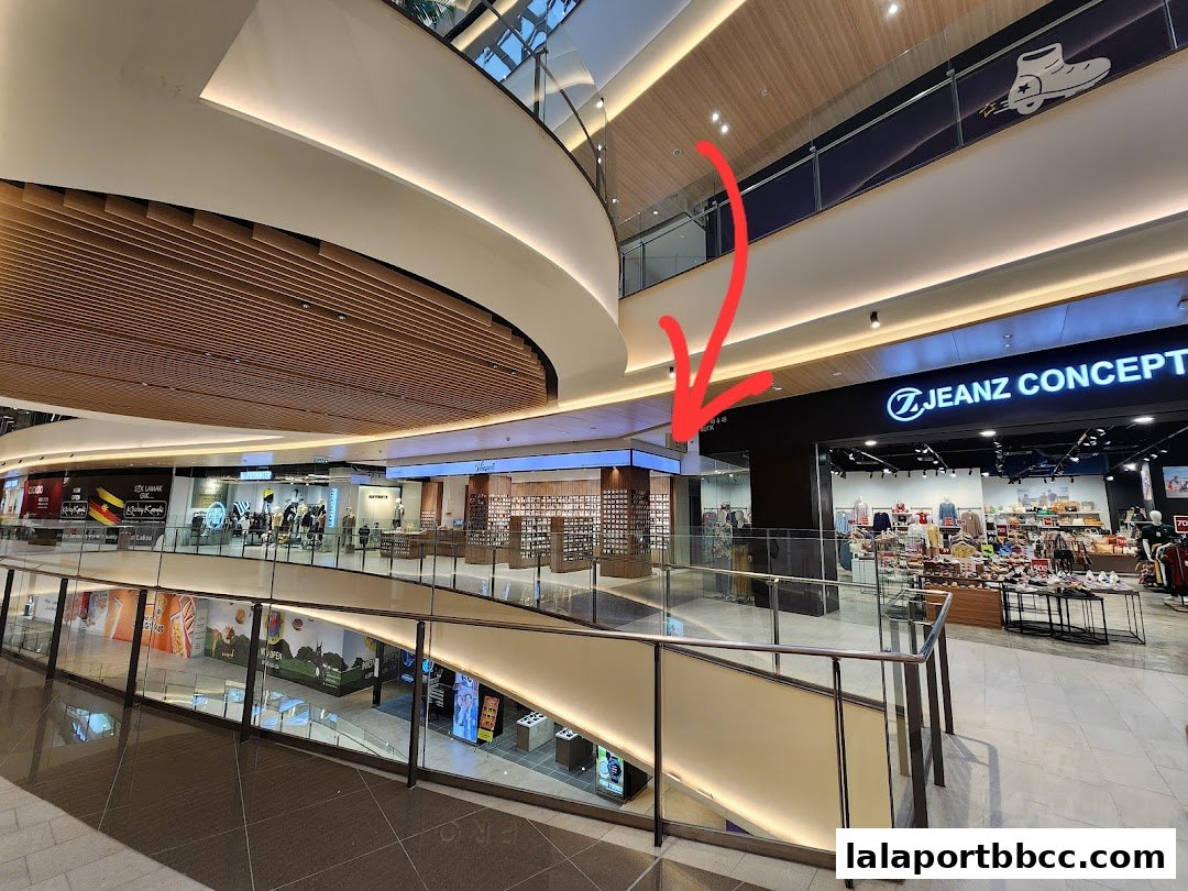 Interior view of a modern shopping mall with various retail stores visible.