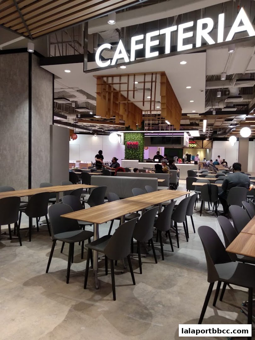 Interior view of a modern cafeteria with ample seating and a prominent 'CAFETERIA' sign.