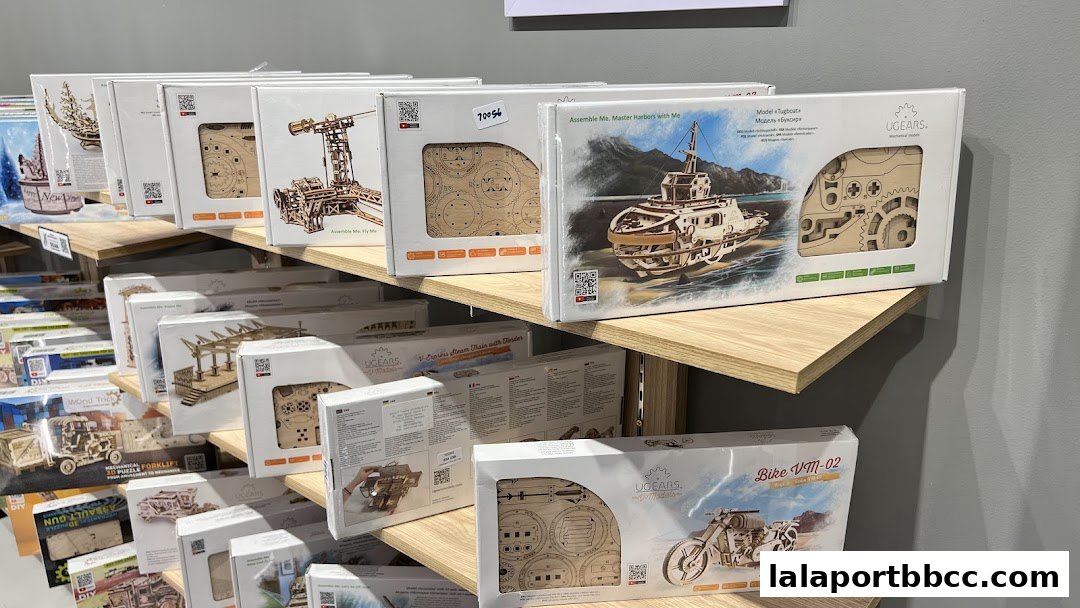 Shelves filled with UGEARS mechanical model kits, including a tugboat and motorcycle.