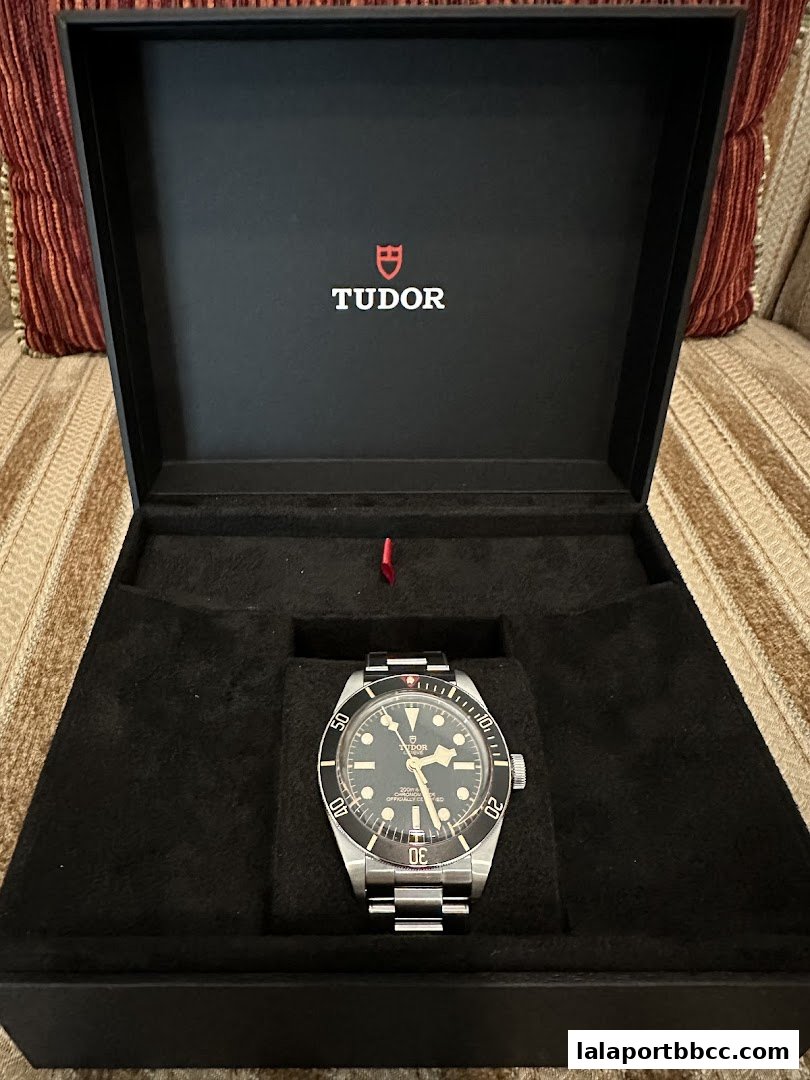 A Tudor watch displayed in its black presentation box with the brand logo.