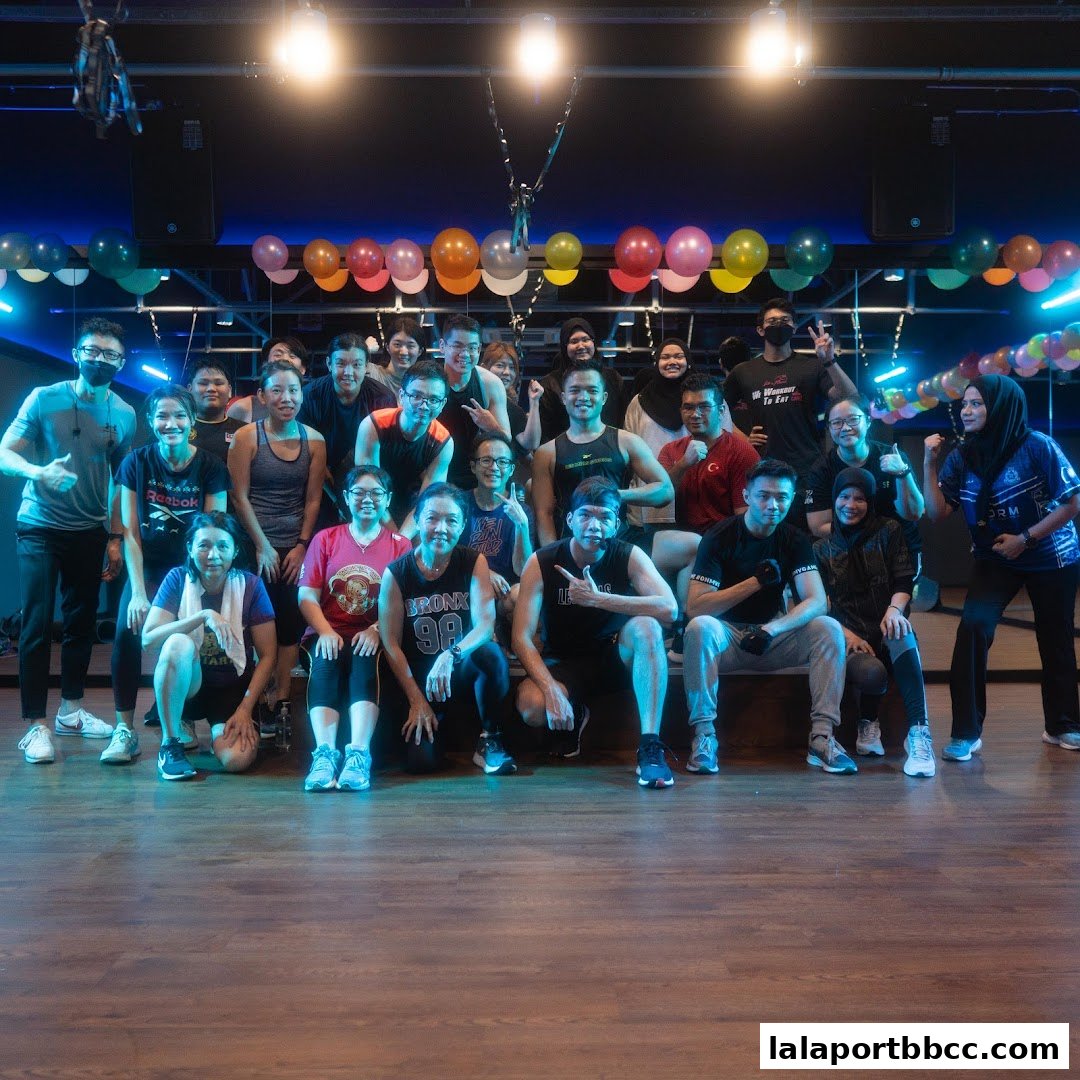 A group of people posing for a photo in a fitness studio with balloons in the background.