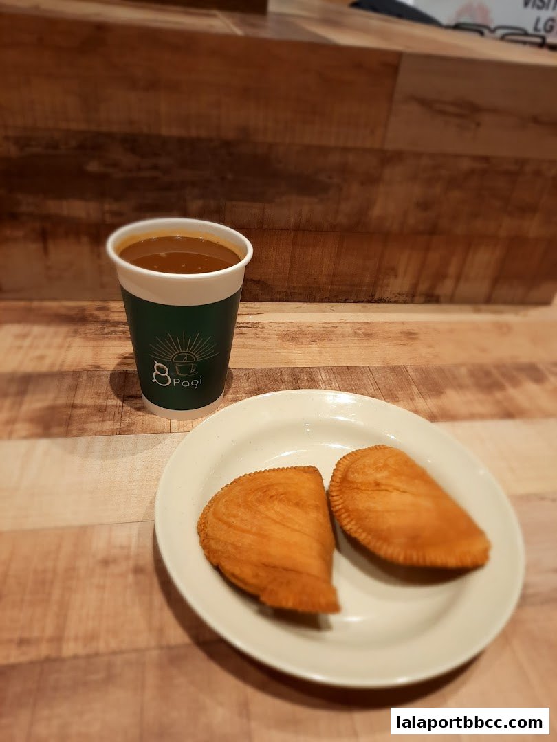 A cup of coffee and two pastries on a plate, set against a wooden background.