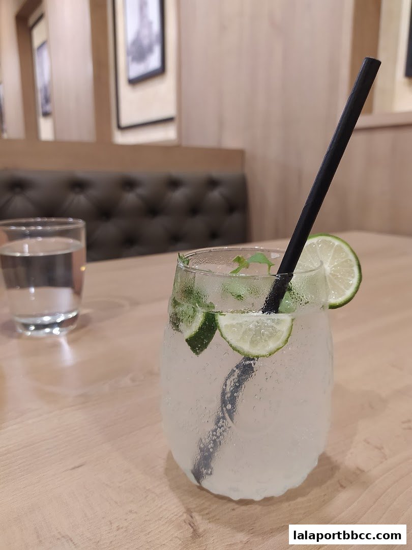 A refreshing drink with lime and mint on a wooden table at a steakhouse.