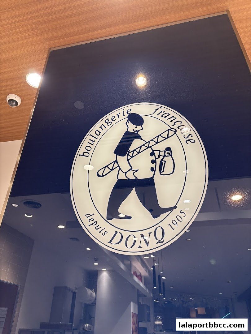 The logo of DONQ Mini One, a French bakery, is displayed on a dark blue surface.