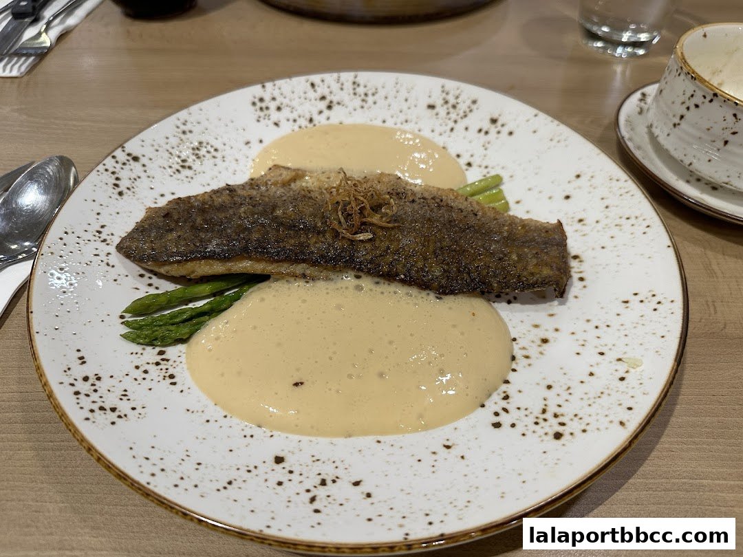 A beautifully plated dish of pan-seared fish with asparagus and a creamy sauce.