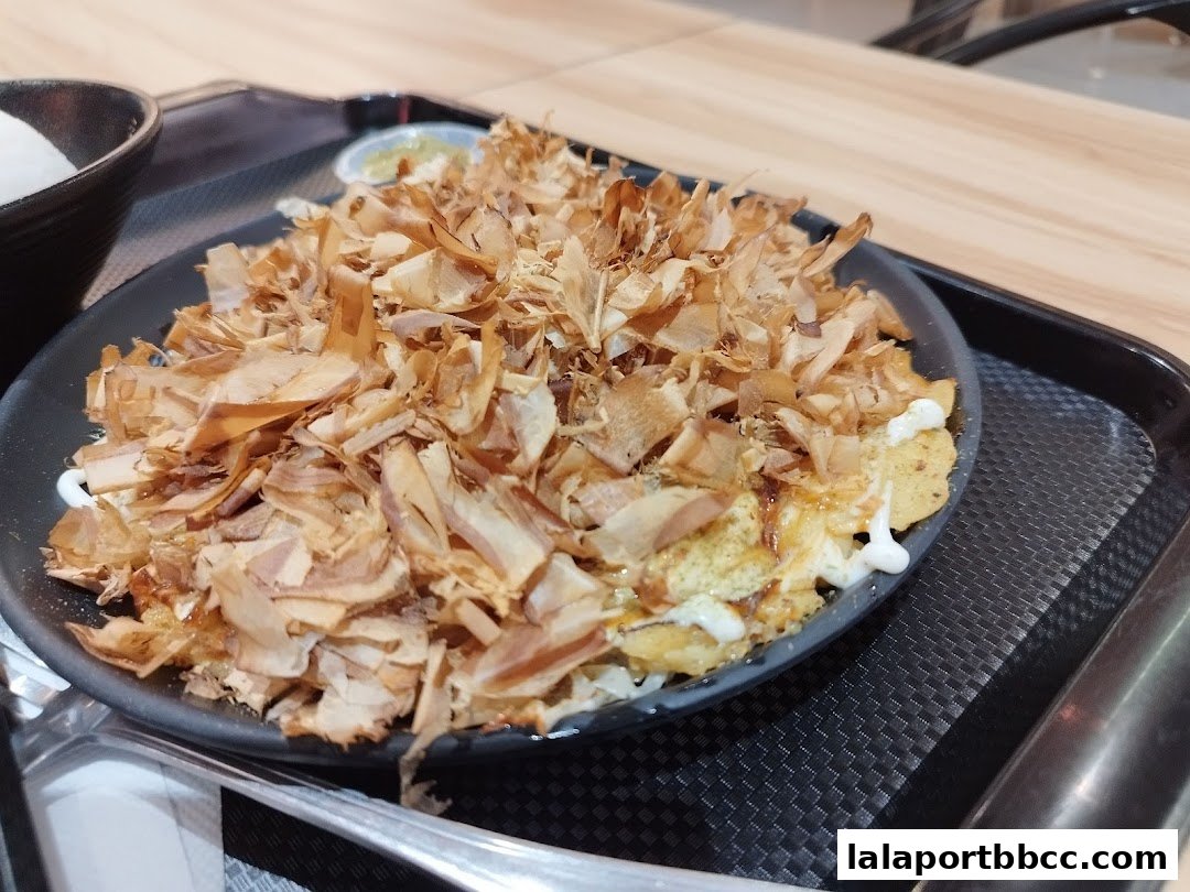 A close-up of a delicious Japanese dish topped with bonito flakes and sauce.