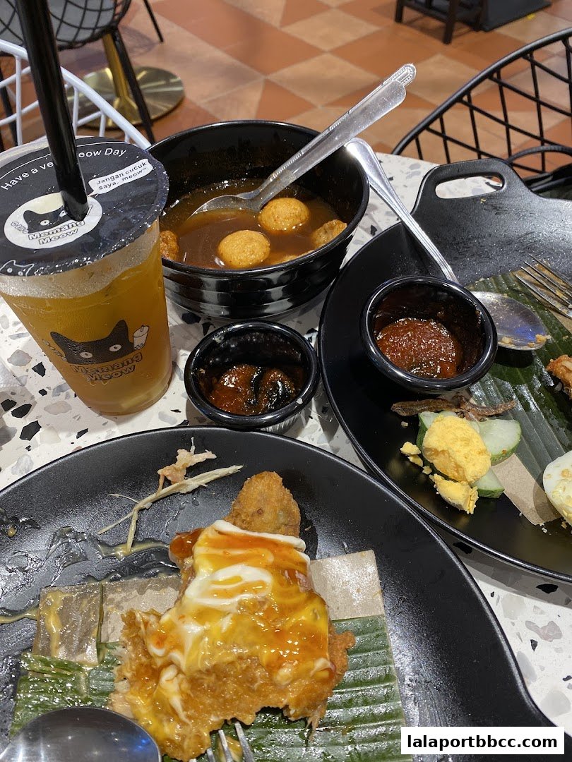 A close-up of a meal with a drink, featuring fried food, soup, and condiments.