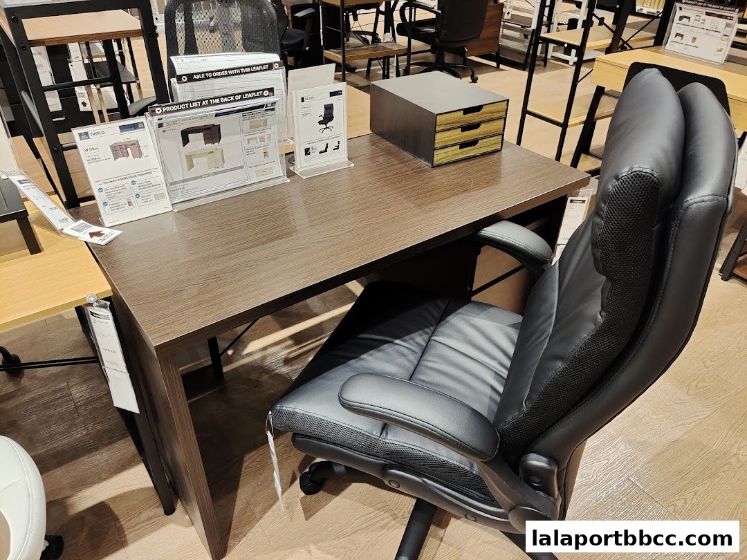 A desk and office chair are displayed in a retail store, with product information leaflets.