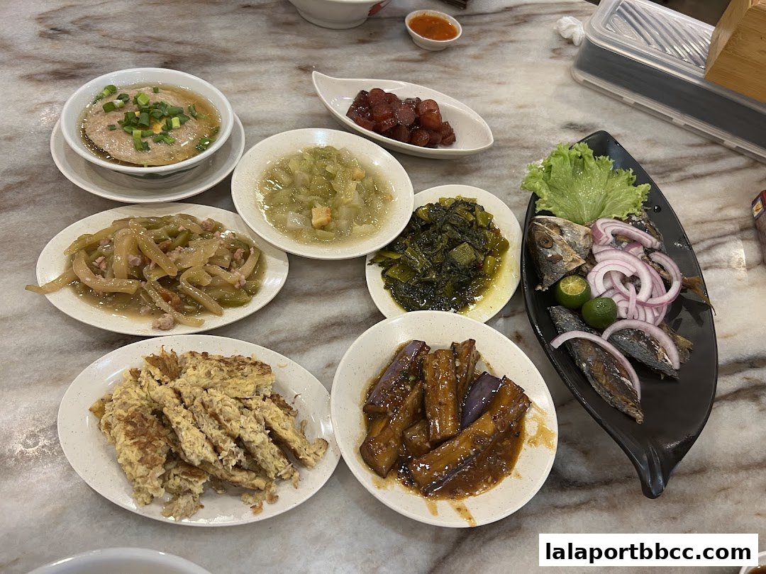 A spread of various Teo Chew dishes, including fish, vegetables, and omelets, served on a marble table.