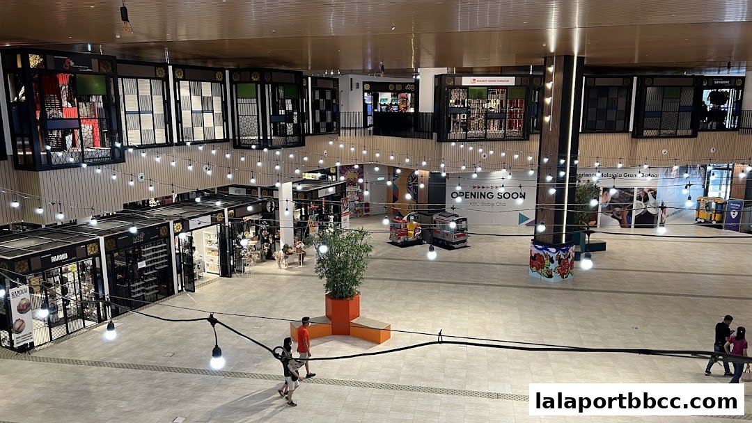 A wide shot of a modern shopping mall interior with various shops and decorative lighting.