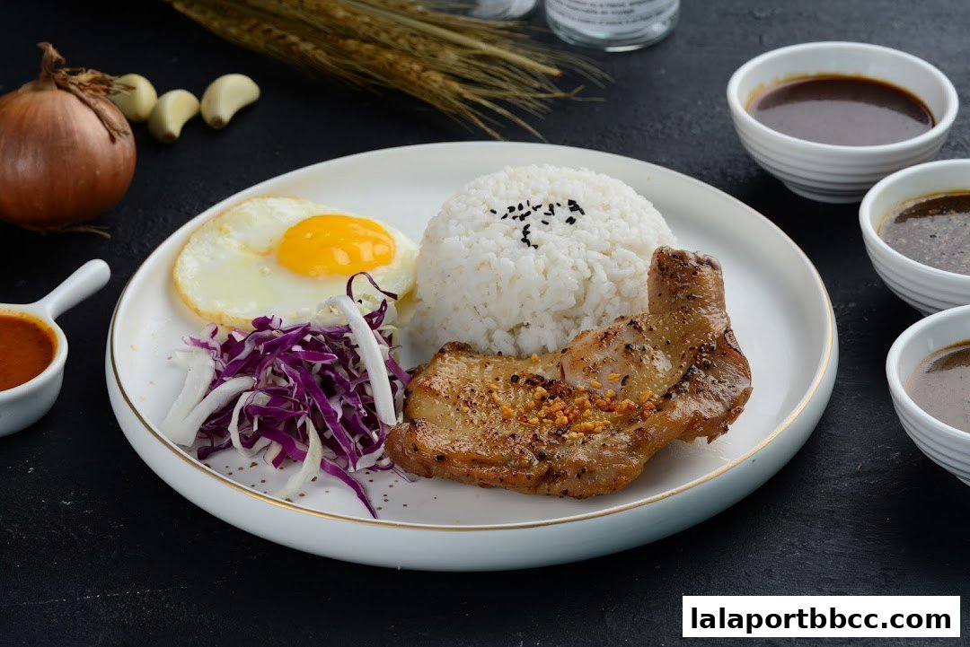 A delicious chicken meal with rice, fried egg, coleslaw, and dipping sauces.
