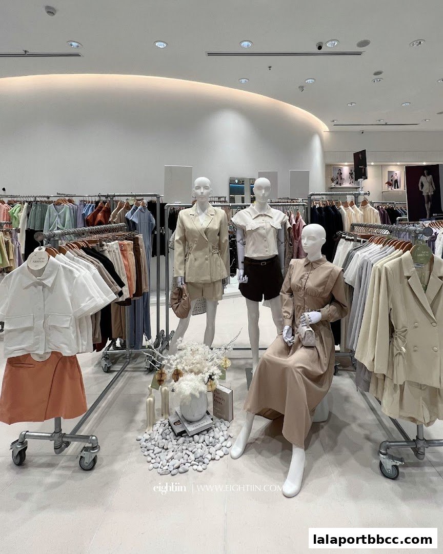 Mannequins display stylish outfits in a well-lit fashion store with racks of clothing.