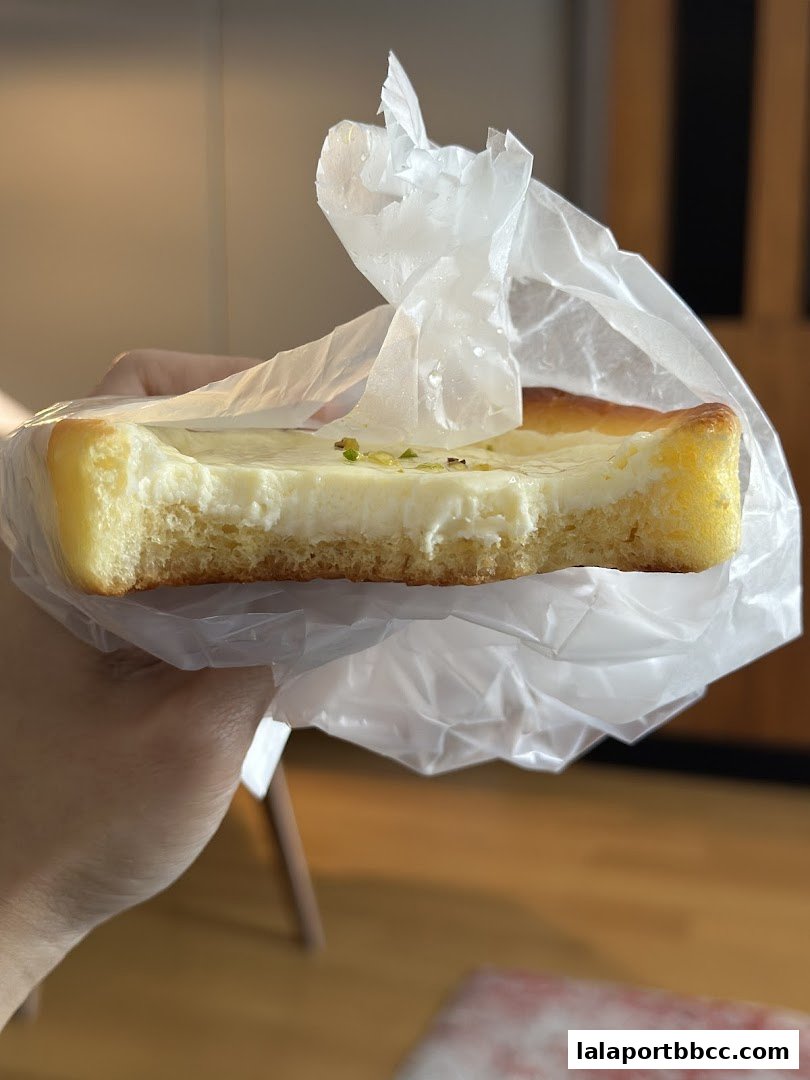 A hand holds a delicious-looking pastry with creamy filling and a bite taken out.
