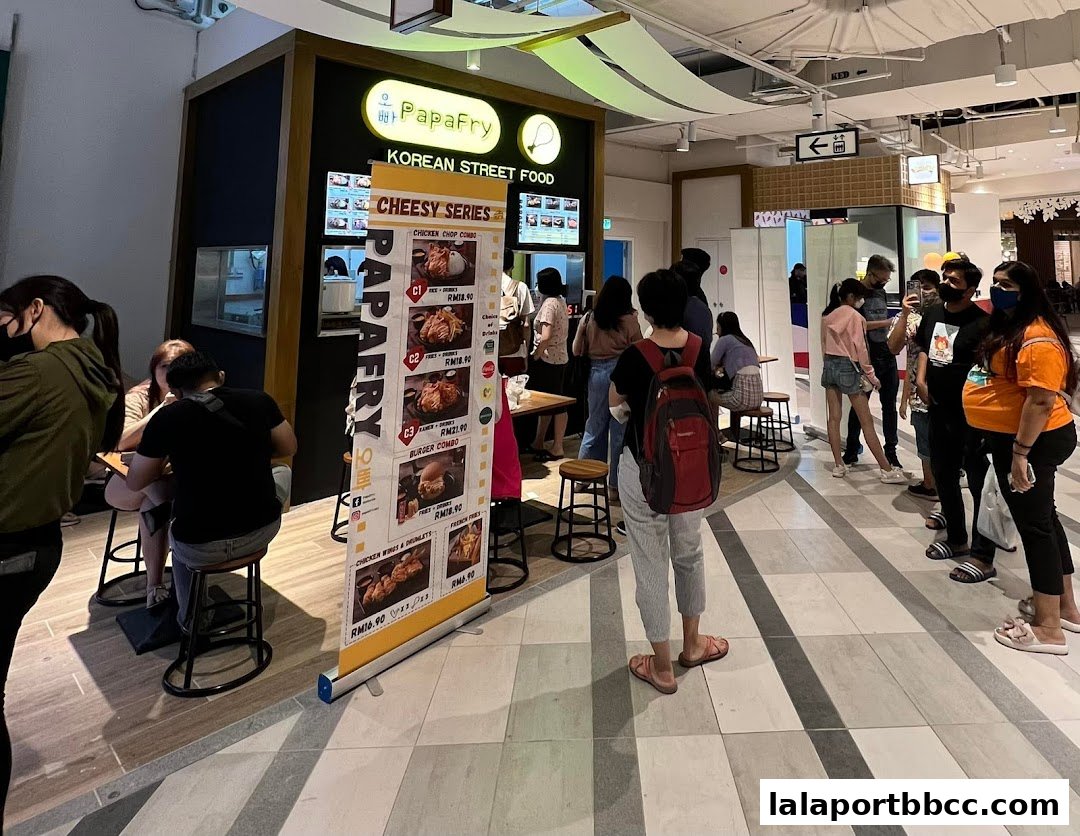 A PapaFry Korean Street Food stall with customers queuing and a menu display.