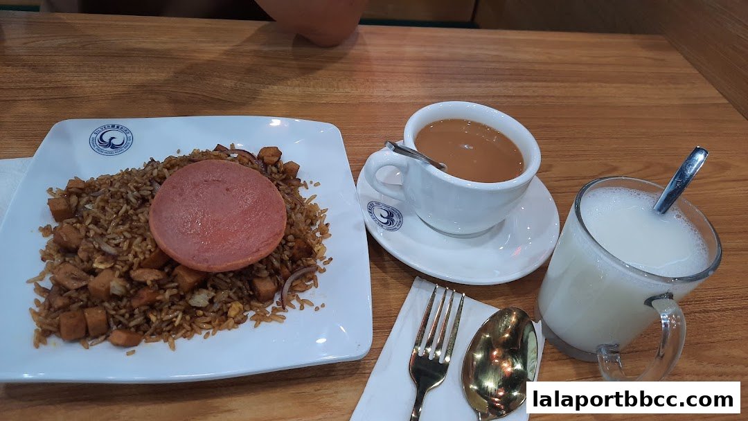 A plate of fried rice with spam, a cup of milk tea, and a glass of milk.