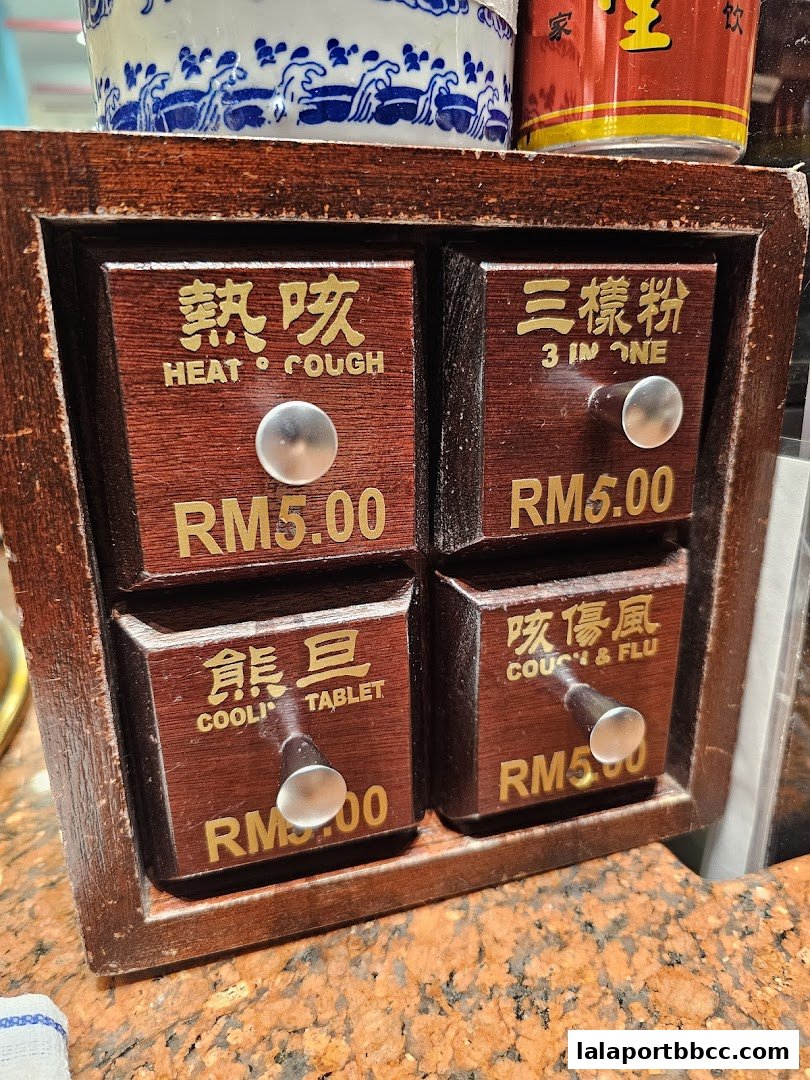 A wooden cabinet with four drawers, each labeled with traditional Chinese medicine for common ailments.