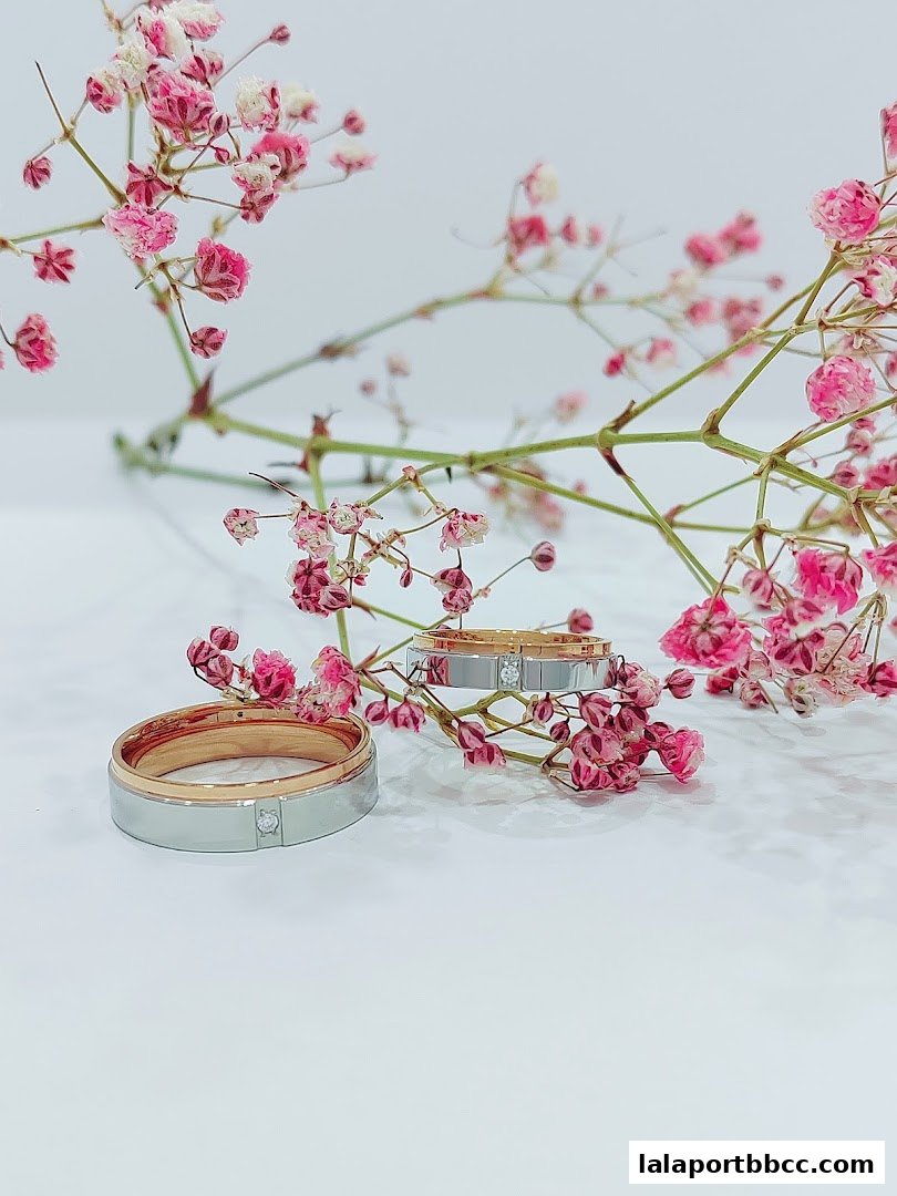 Two elegant rings with diamonds, adorned with delicate pink flowers on a white background.