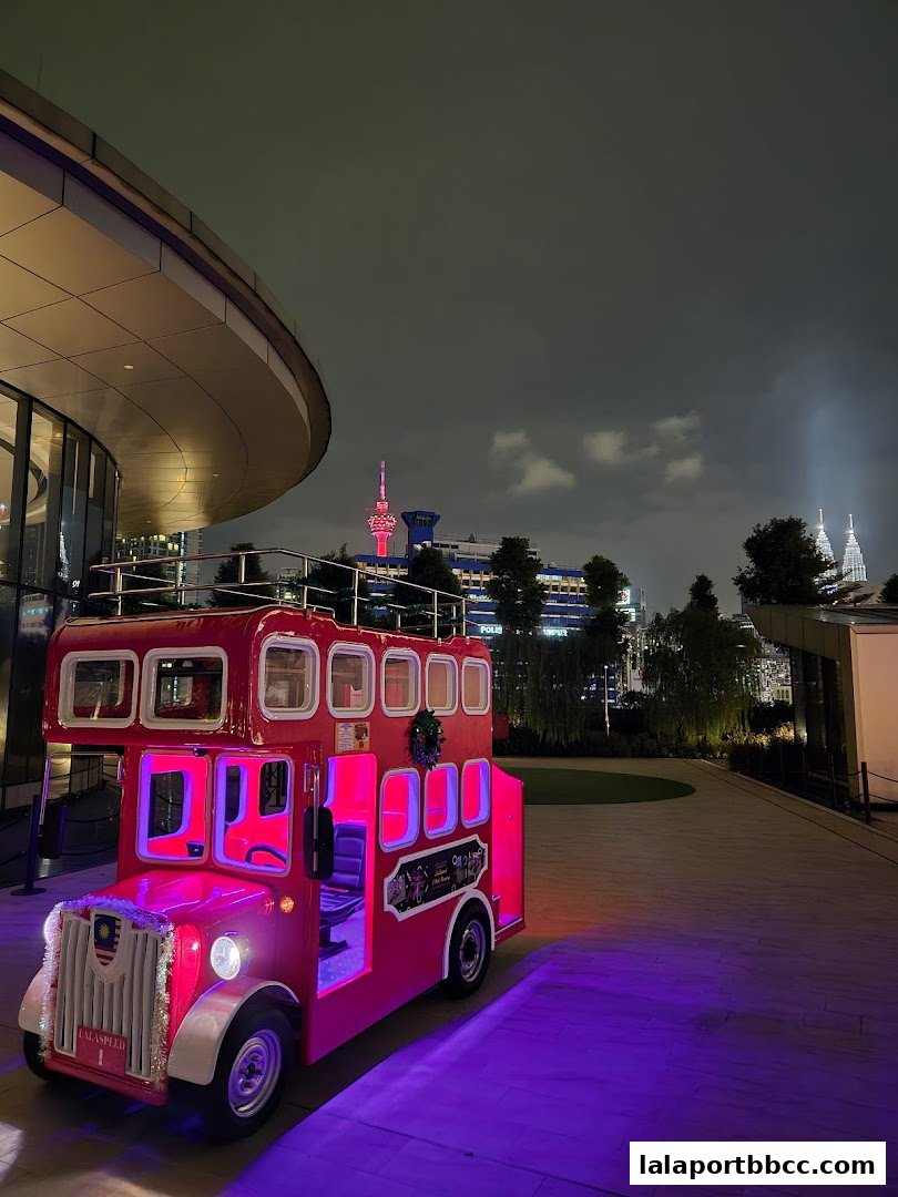 A red double-decker bus attraction illuminated with purple lights at night.