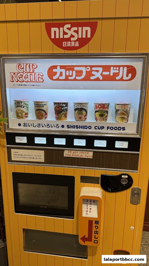 A Nissin Cup Noodle vending machine displaying various ramen flavors and cup foods.