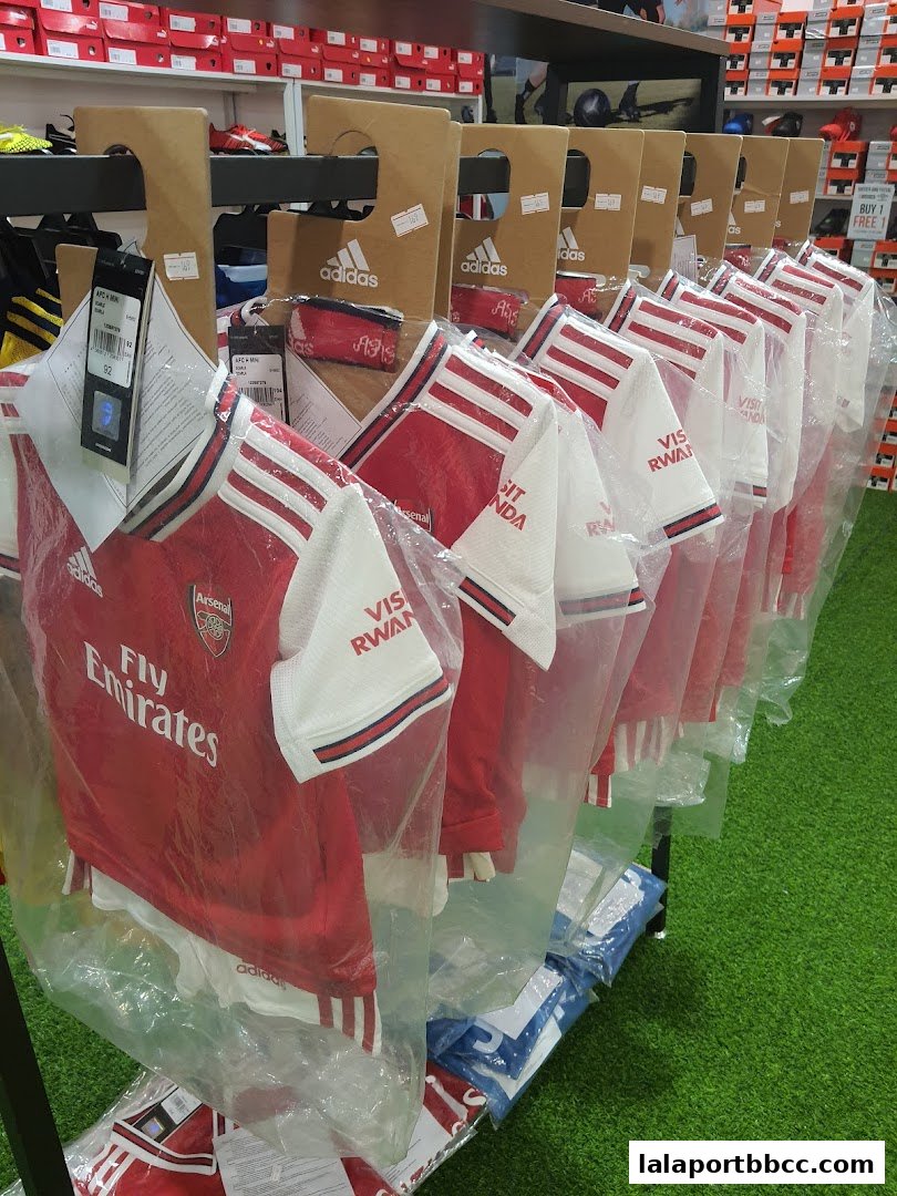 Rows of Arsenal football jerseys displayed in plastic packaging on a rack.