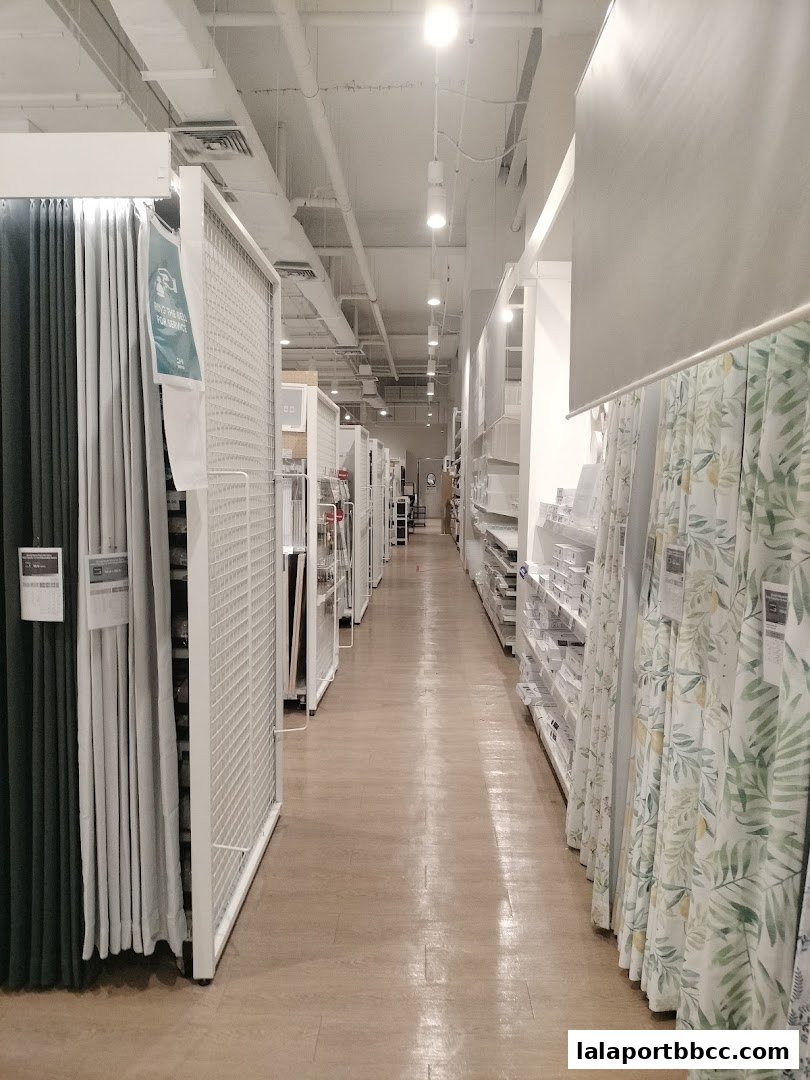 A long aisle inside a NITORI store, showcasing curtains and shelving units.