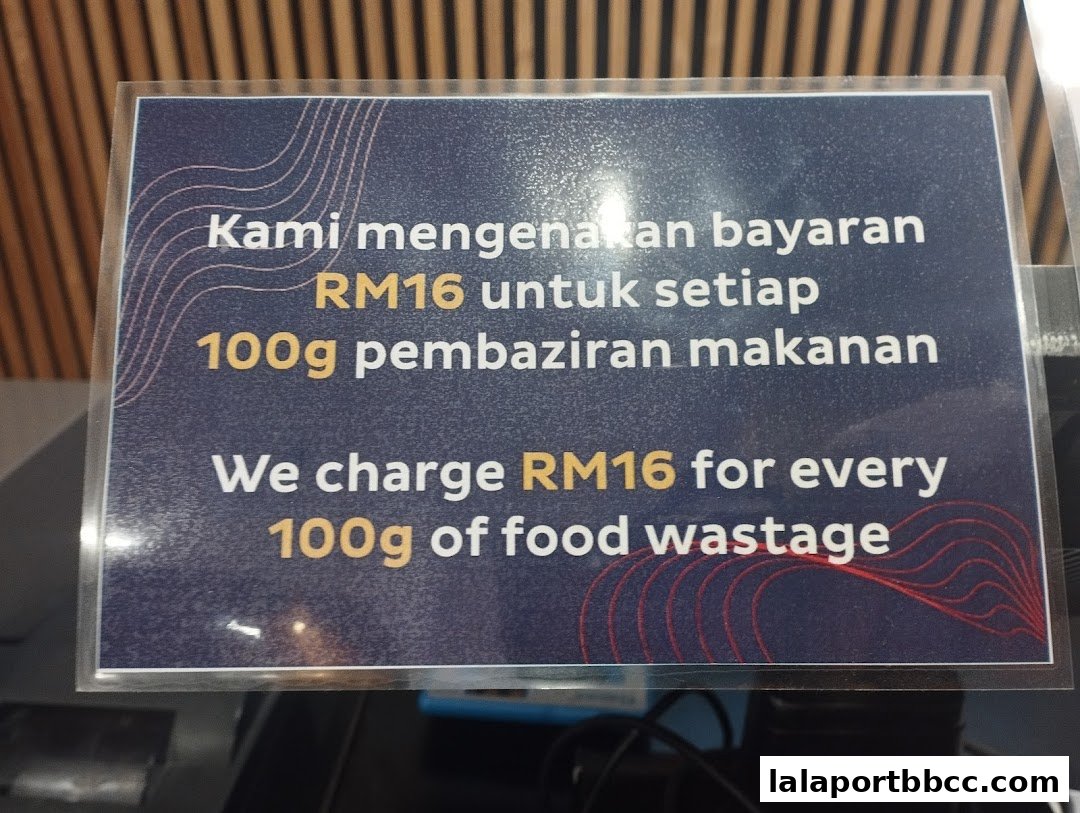 A sign stating a charge of RM16 for every 100g of food wastage.