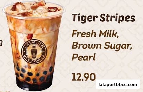 A close-up of a 'Tiger Stripes' drink from Dee Coffee, featuring fresh milk, brown sugar, and pearls.