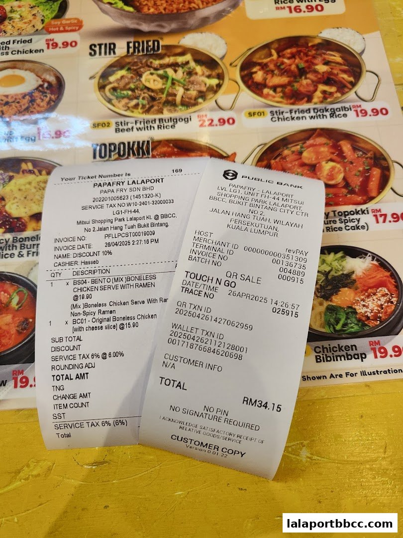 A receipt from PapaFry Lalaport is placed over a menu featuring Korean dishes like Stir-Fried Dakgalbi and Chicken Bibimbap.