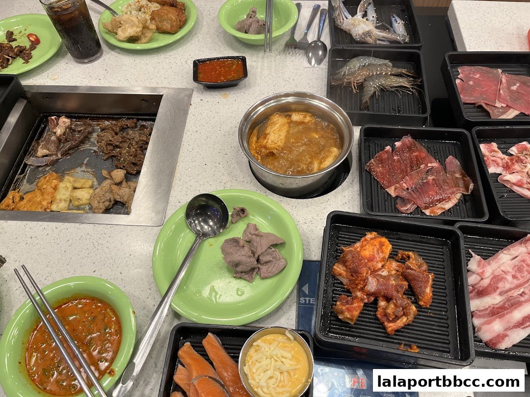 A table laden with various Korean BBQ ingredients, including marinated meats, seafood, and dipping sauces.