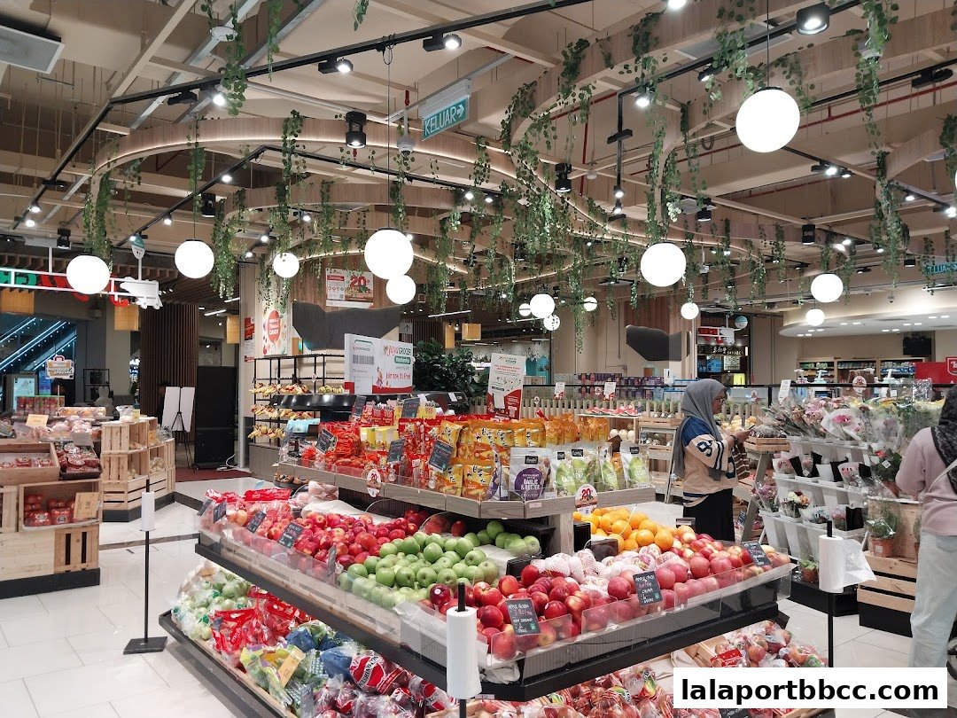 A brightly lit grocery store interior with fresh produce displays and shoppers.