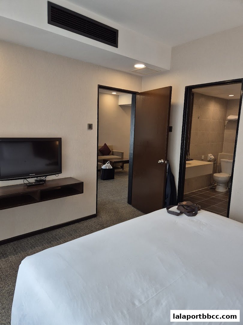 A hotel room with a bed, TV, and doors leading to a living area and bathroom.