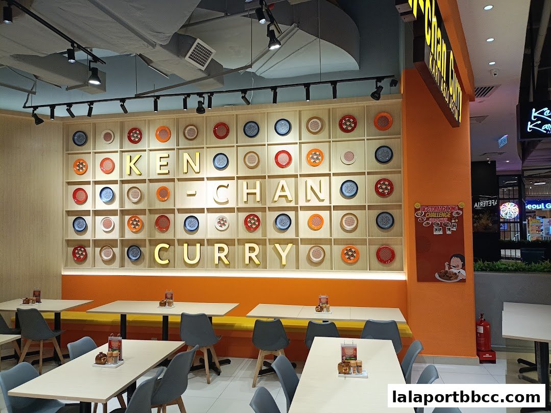 Interior of Ken-Chan Curry restaurant with tables, chairs, and a decorative wall.