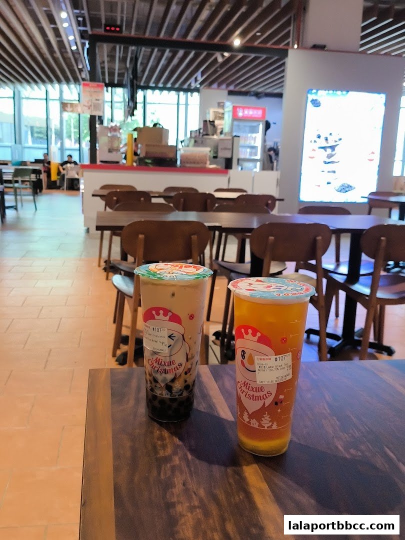 Two Mixue drinks, one with boba and one with lemon tea, sit on a wooden table.