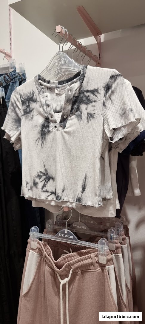 A close-up of a tie-dye t-shirt and sweatpants on hangers in a store.