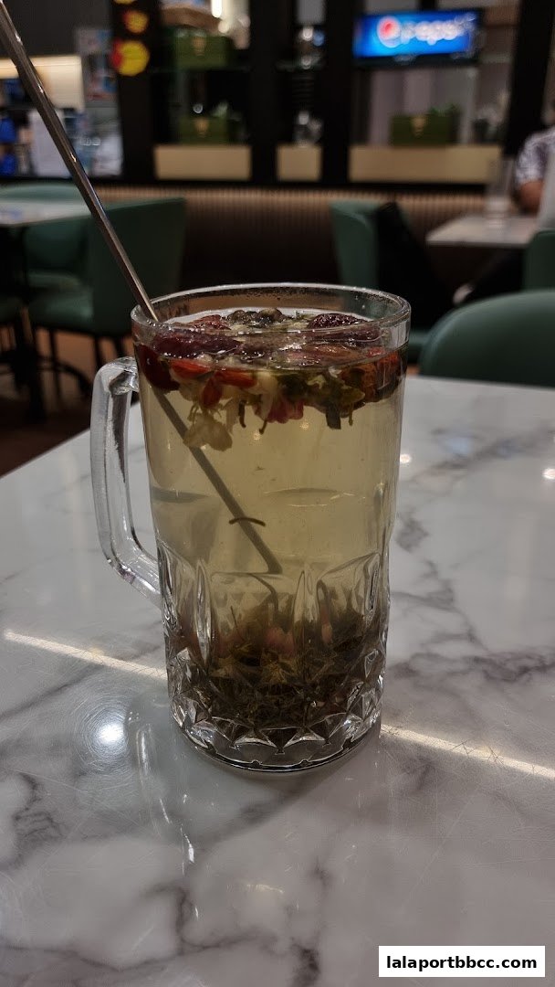 A glass mug filled with a refreshing herbal tea, garnished with dried fruits and flowers.