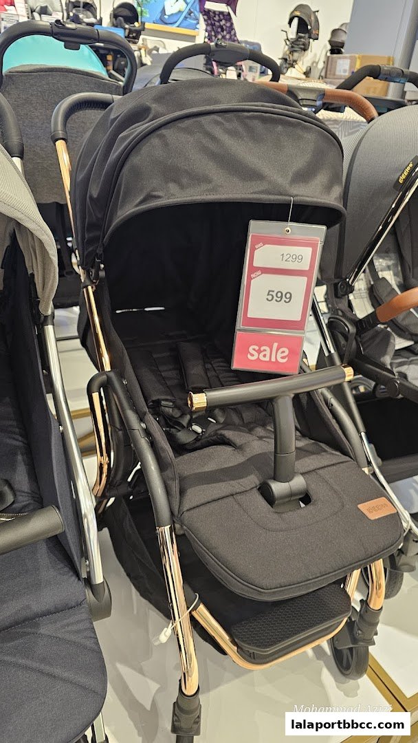 A close-up of a black baby stroller with rose gold accents on sale.