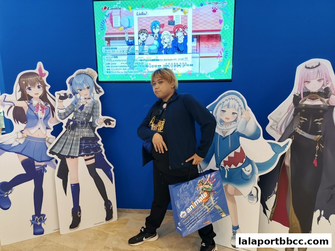 A person poses with cardboard cutouts of anime characters and an Animate shopping bag.