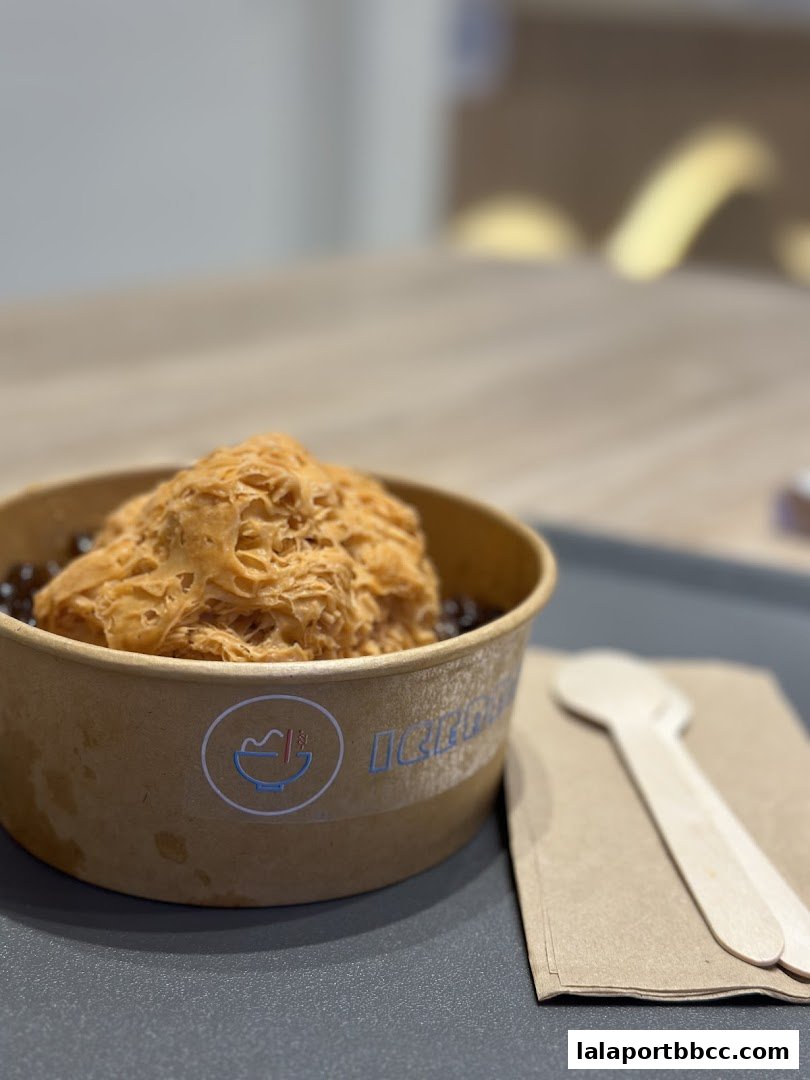 A close-up of a bowl of shaved ice with boba pearls and two wooden spoons.
