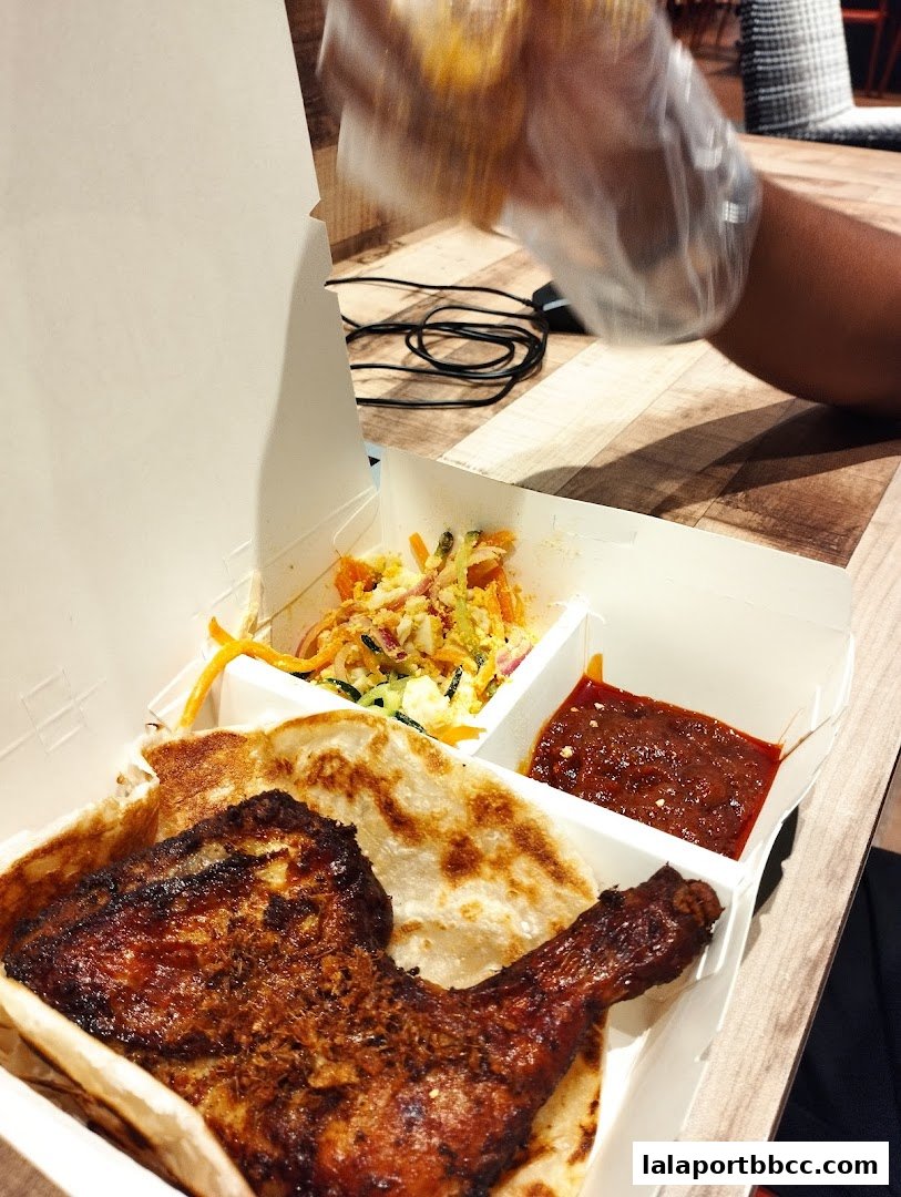 A delicious meal featuring grilled chicken, flatbread, salad, and dipping sauce in a takeaway box.
