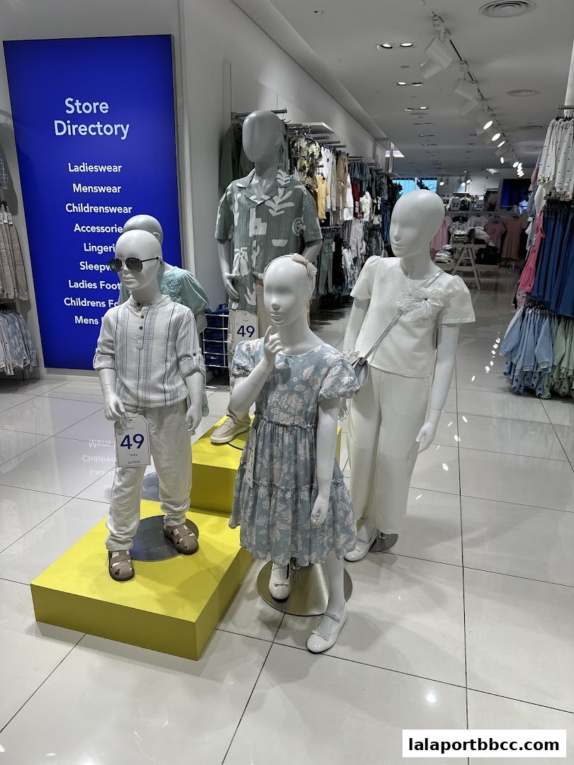 Mannequins dressed in stylish children's and adult clothing inside a bright retail store.