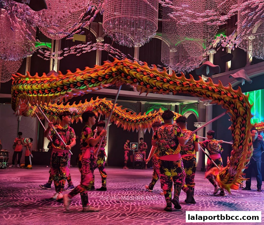 Performers in colorful outfits dance with a large dragon in a beautifully decorated venue.