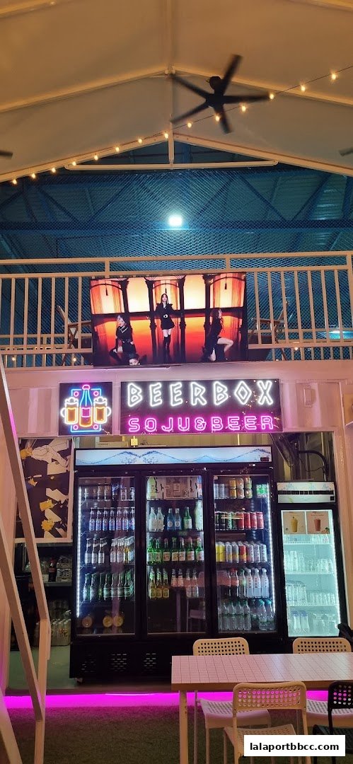 Beer Box shop with neon signs, refrigerators full of drinks, and seating area.