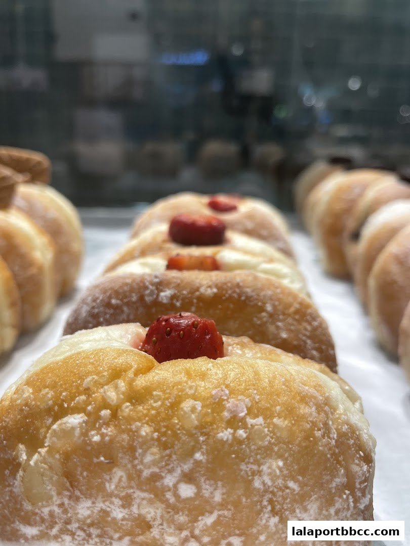 Close-up of freshly baked donuts with powdered sugar and strawberry toppings.
