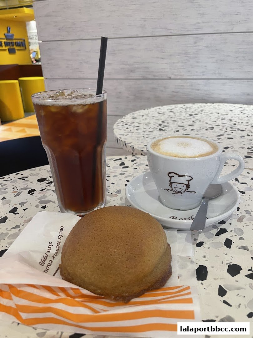 A Rotiboy bun, iced coffee, and a cappuccino are displayed on a table.