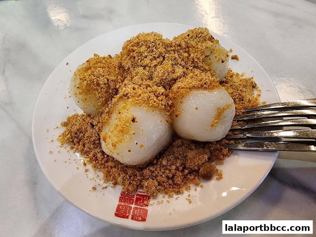 A plate of glutinous rice balls topped with crushed peanuts, served with a fork.