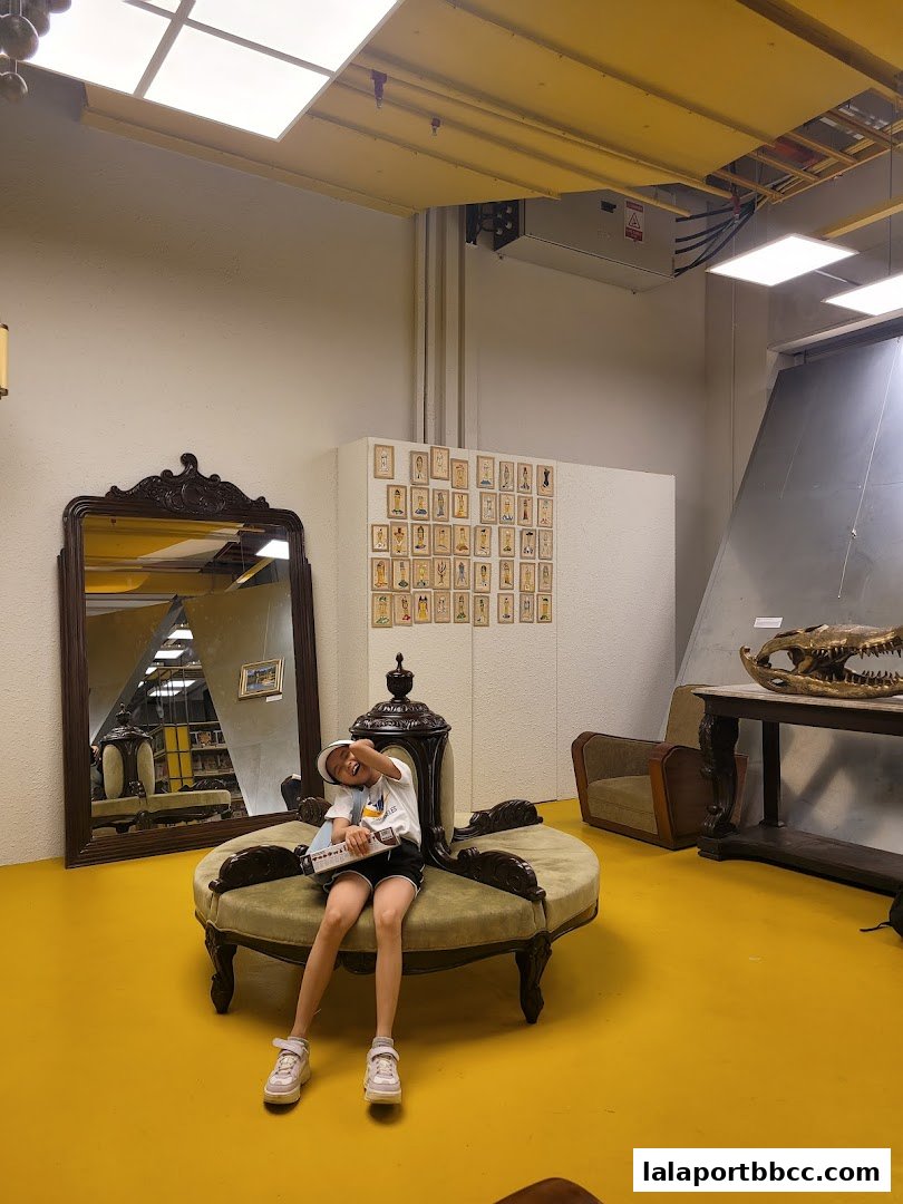 A child sits on a vintage couch in a room with a large mirror and artwork on the wall.